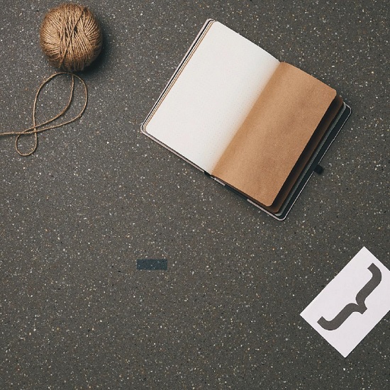 A bird view of a Quartzforms Pebble Dark Grey quartz worktop with a book and yarn