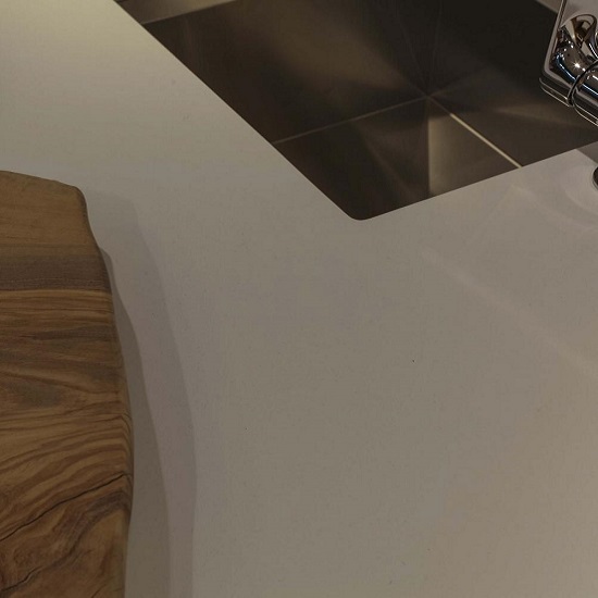 A photo of a worktop in QF Light Beige spacco finish quartz, an undermount sink, a and a wooden chopping board
