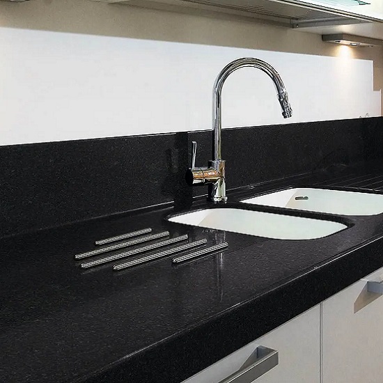 A kitchen worktop in Absolute Black granite with hot rods and a white wall