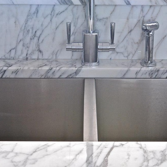 a photo of an Arabescato marble worktop, two sink cut outs, and a faucet