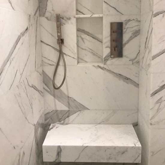 a photo of a bathroom with Calacatta Bettogli marble walls and a bench