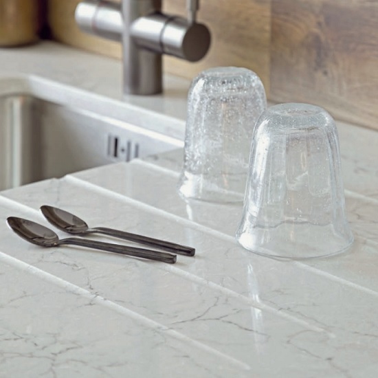 a polished CRL Quartz Vicenza kitchen worktop with two glasses and two tea spoons
