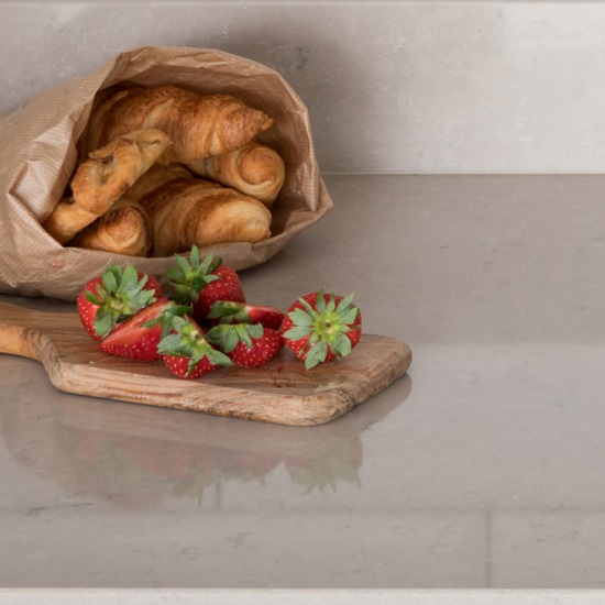 a kitchen worktop made from CRL Quartz Antico with matching upstands, strawberries and a bag of croissants