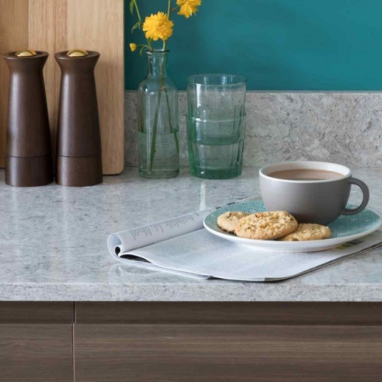 a blue kitchen with CRL Quartz Montana Gris 20mm thick worktops, a coffee cup, biscuits, glasses and vases