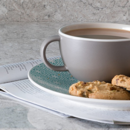 a CRL Quartz Montana Gris worktop in a polished finish, a coffee cup and a plate with biscuits