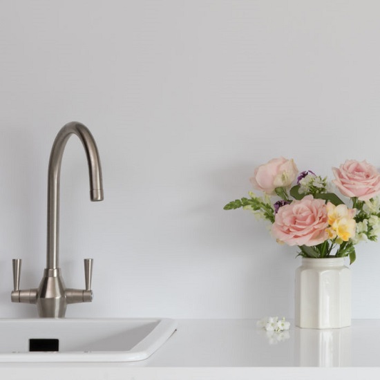 a splashback in CRL Quartz Polar White, matching worktops, a tap and a vase with roses