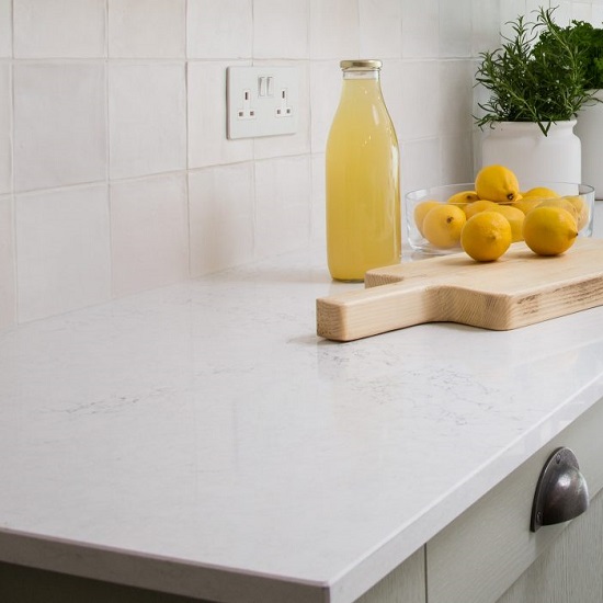 a 30mm thick CRL Quartz Statuario Bianco worktop in a white kitchen with sage green cabinets