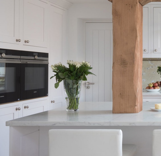 a CRL Quartz Verona island worktop with a plant on it in a white kitchen