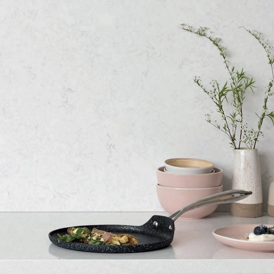 a CRL White Water quartz worktop and splashback, a pan, a plate, bowls and a plant pot