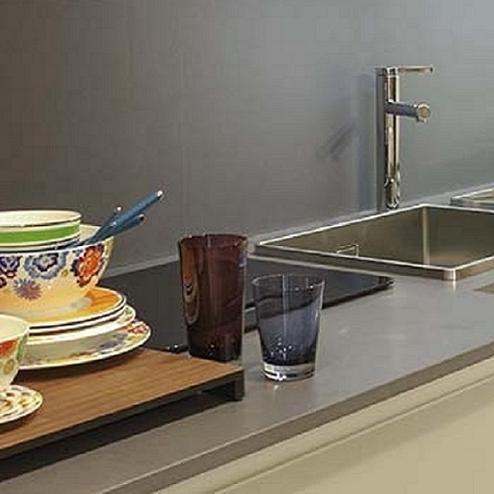 a photo of beige kitchen cabinets with Quartzforms Cloudy Portland Grey quartz worktops and splashbacks with glasses, a bowl and plates