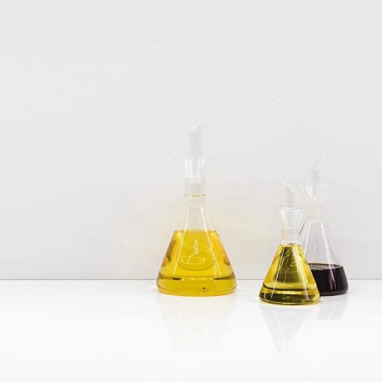 a kitchen worktop with three bottles containing oil, vinegar, and balsamic on top of a Xtone Moon White worktop