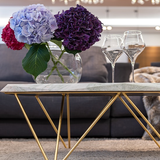 a photo of a Calacatta Arni Marble worktop on a coffee table, flowers and glasses