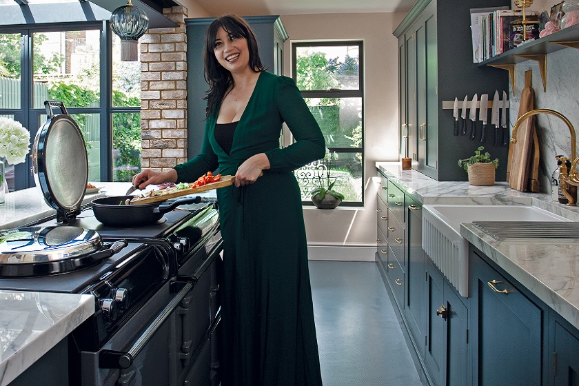A photo of Daisy Lowe in a blue Victorian kitchen wth Calacatta marble worktops