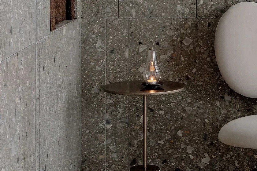 a photo of a wall cladding in Agglotech terrazzo Aggloceppo, a table and a candle light