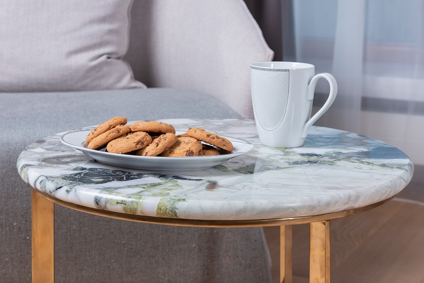 a photo of a Primavera green marble table top, a cup and a plate with biscuits