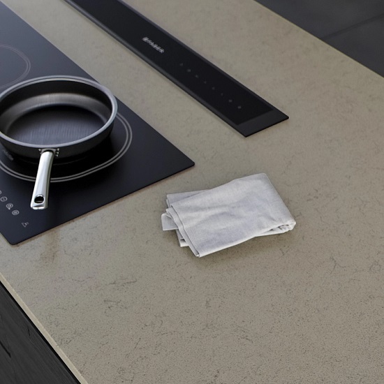 a photo of a Technistone Noble Portland Grey kitchen worktop with a pan on a black hob and a white cloth