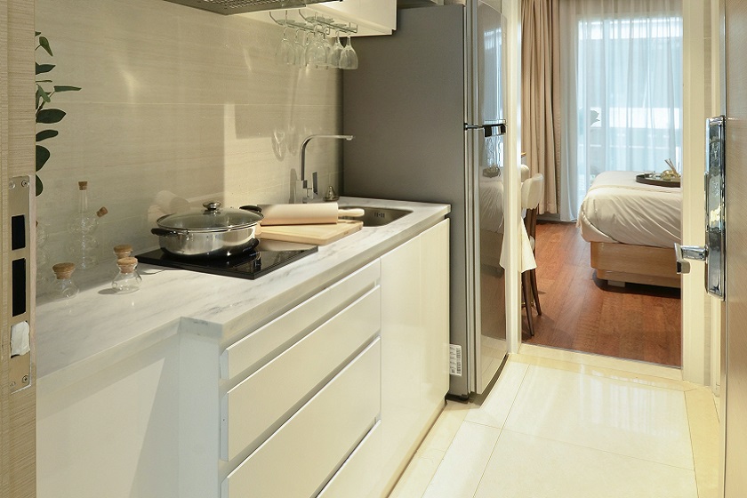 A photo of a white kitchen with 40 mm thick marble worktops, a black ceramic hob and pots 