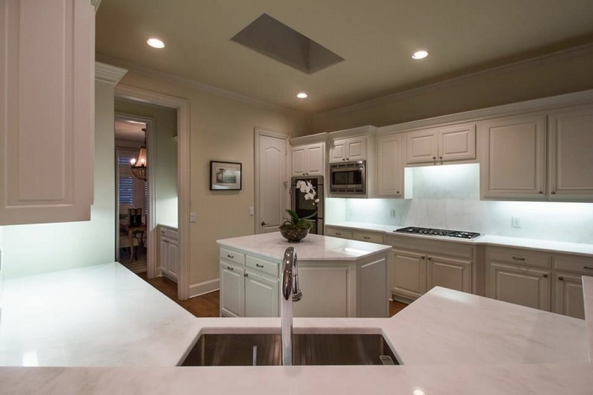 A photo of a transitional style kitchen with beige cabinets and Bianco Rhino Marble worktops
