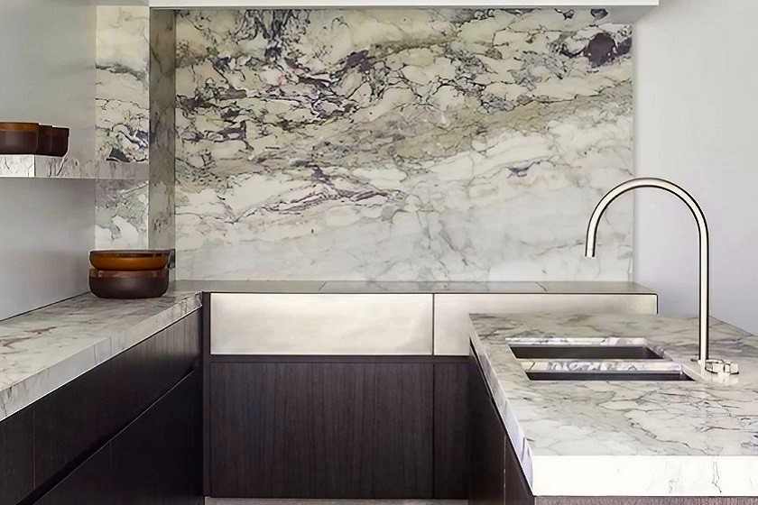 A compact kitchen with dark cabinets and Breccia Capraia marble worktop and backsplashes