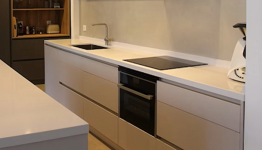 A kitchen with Silestone Miami White worktops, white cabinets and black appliances
