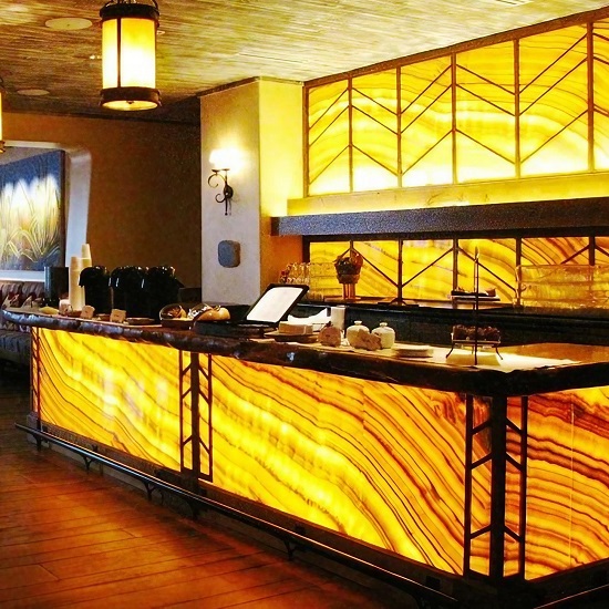 a photo of Orange Onyx bar countertops backlit and a pendant light