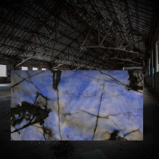 a photo of a Sky Blue Onyx backlit slab in a dark warehouse