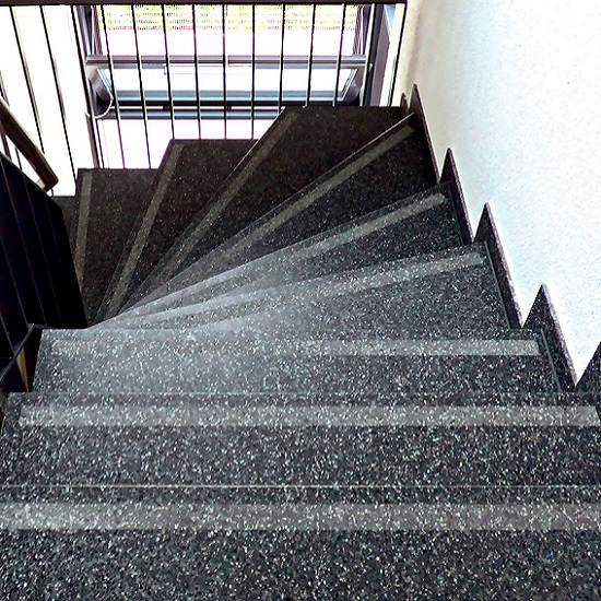a photo showing grey and black terrazzo stairs in a white corridor