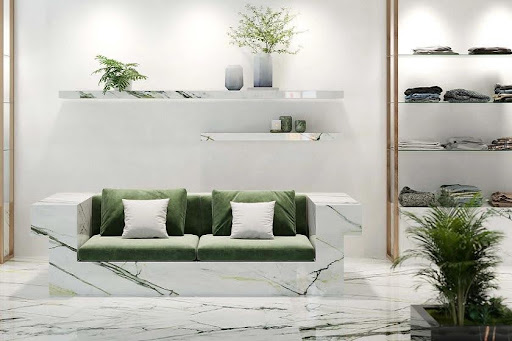 A green couch in a room adorned with Xtone Calacatta Green and various plants in a white room