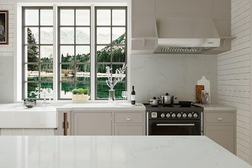 A kitchen with a large window and Unistone Misterio Gold veined worktops and splashaback