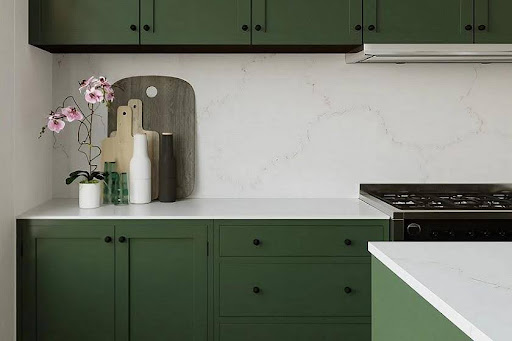 A kitchen with green cabinets and Unistone Misterio Gold worktops
