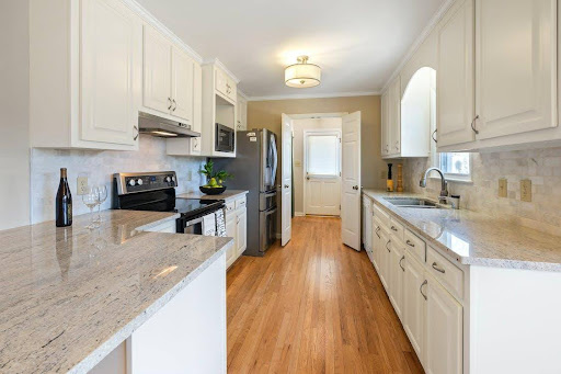 A kitchen with white cabinets and River White Granite worktops