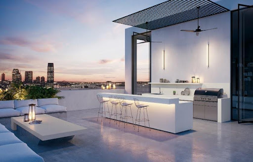 A white bar with stools on a rooftop decorated with Caesarstone outdoor quartz Palm shade