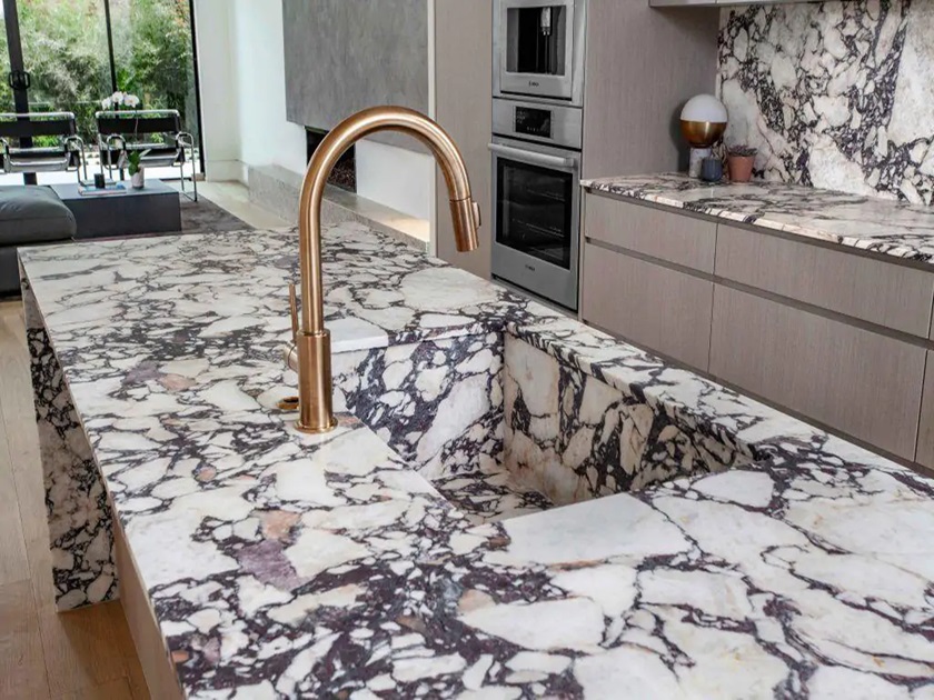 a photo of a Calacatta Viola in a modern kitchen with a golden faucet