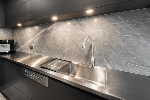 A sink and faucet in a kitchen with Atlantic Grey Marble worktops and baksplash