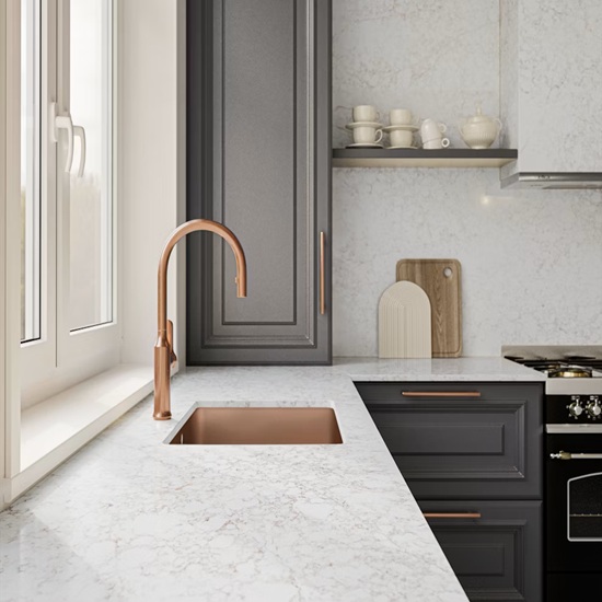 a close-up of a Silestone Riviere Rose worktop and a golden faucet