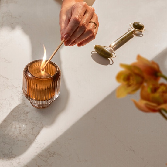 a close-up of a Caesarstone Solenna and a hand lighting a candle