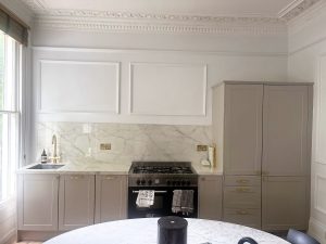 Full view of Ascale Vagli Gold porcelain kitchen with stove, sink, and round table in Holloway renovation by Worktop Library
