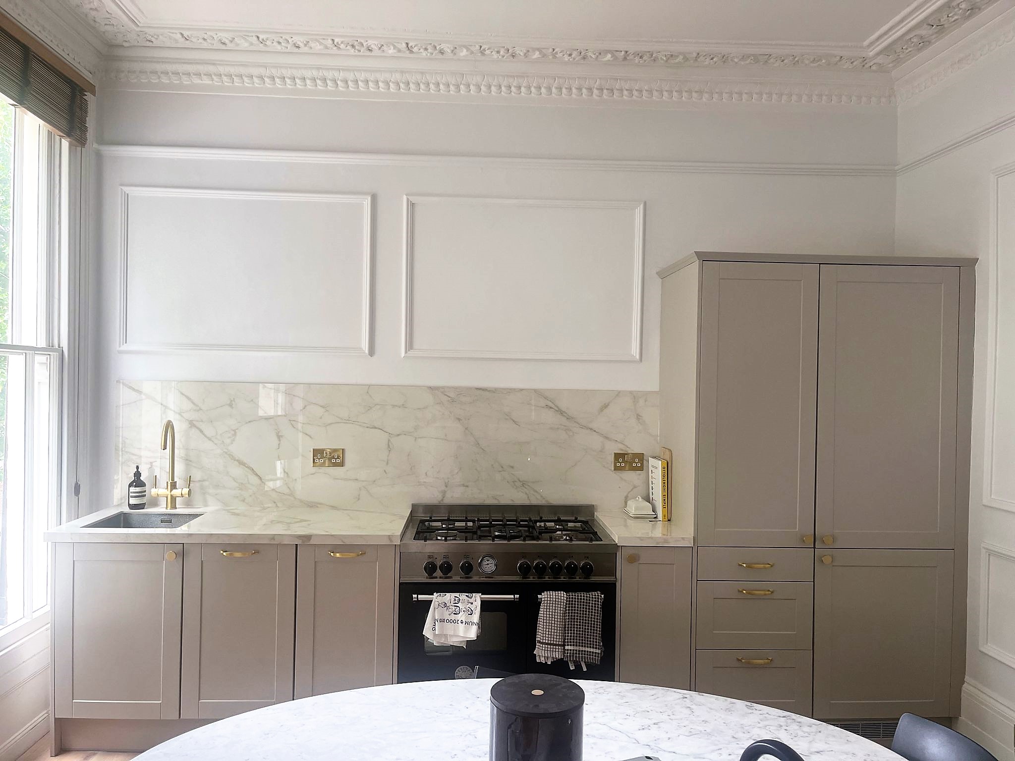 ull view of Ascale Vagli Gold porcelain kitchen with stove, sink, and round table in Holloway renovation by Worktop Library