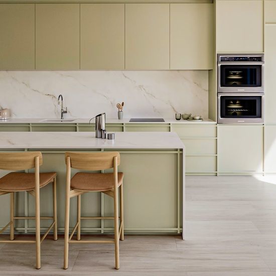 Dekton Keena in a modern green kitchen with island, sink, and bar stools