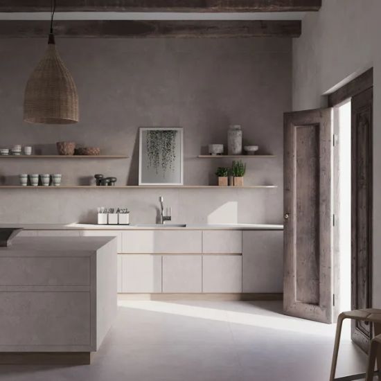 Neolith Artisan kitchen island and worktops in gentle grey, with pendant light, shelves, vases, and rustic wooden door in light-filled space