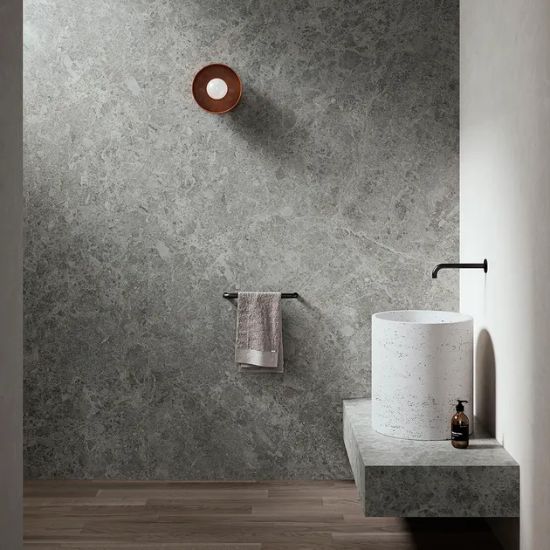 Neolith Cappadocia Sunset bathroom walls and vanity in grey marble effect with towel rail, cylindrical sink, soap, and wooden floor