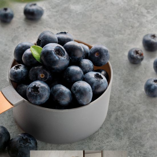 Neolith Cappadocia Sunset worktop close-up with blueberries in grey cup and scattered berries on grey veined surface