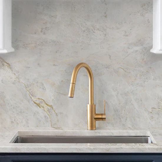 Close-up of Neolith Everest Sunrise splashback and worktop around gold faucet and sink