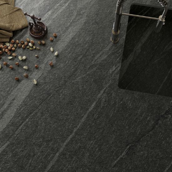 Neolith Ignea kitchen island worktop and splashback in deep grey slate effect, with appliances, linear light, and fruit decor