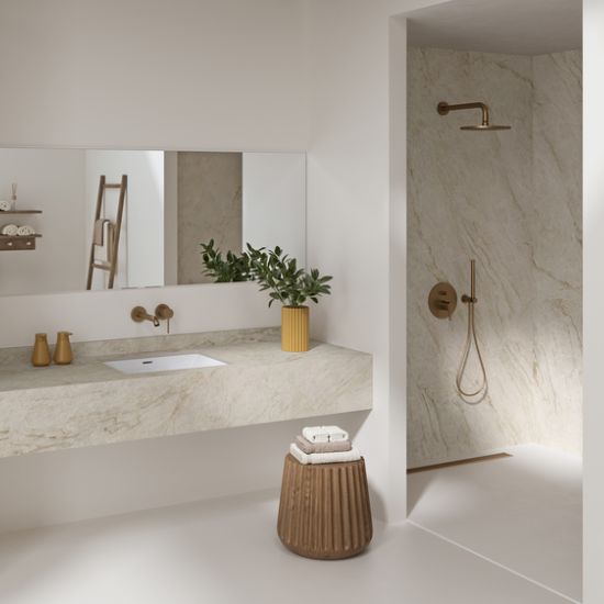 Neolith Taj Mahal bathroom walls and vanity in white quartzite effect with gold taps, ladder shelf, plants, and wooden stool in spa-like setting