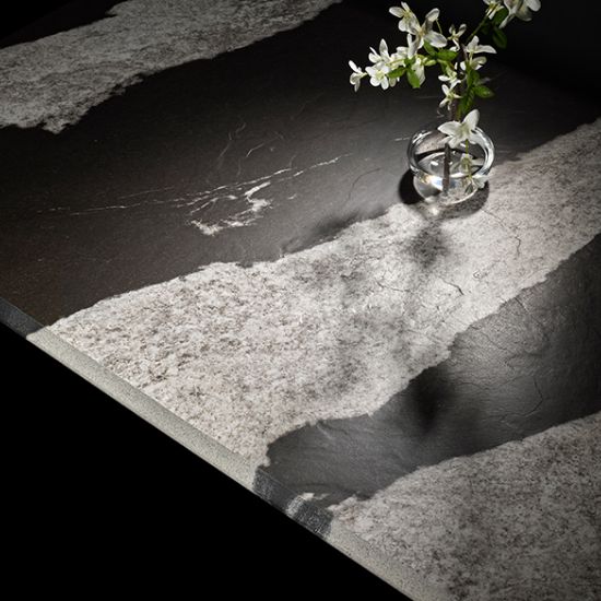 Macro view of Neolith Victoria worktop highlighting black granite effect with white veins and small vase of white flowers