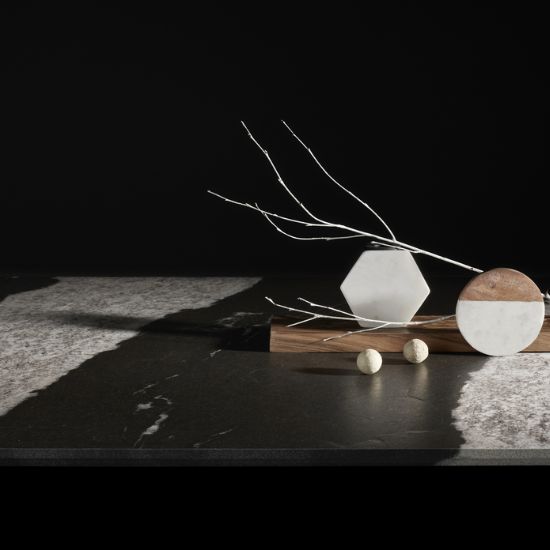 Close-up of Neolith Victoria sintered stone showing deep black with white veining, adorned with branches, marble hexagon, and wooden accents