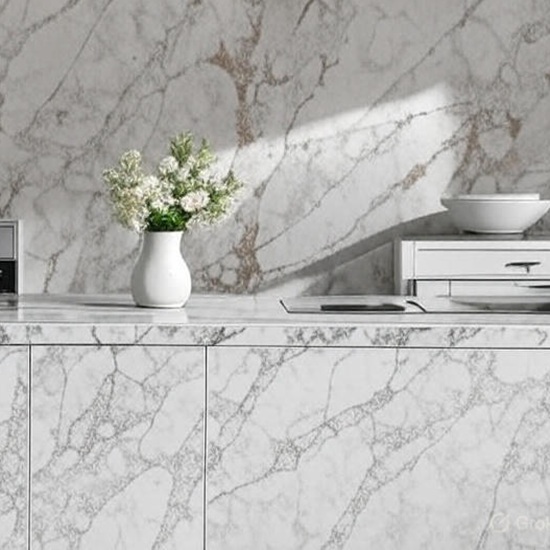 Arabescato Oro quartz worktop in modern kitchen with built-in oven, orange and white flowers, and reflective white surface with gold veins from EssexQuartz Collection