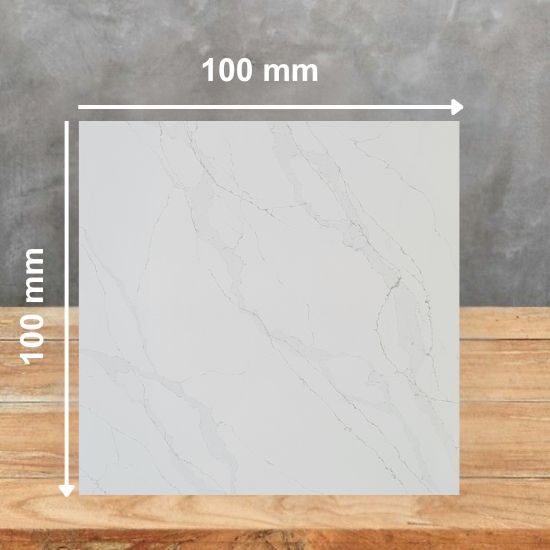 100 mm square sample of Calacatta Gold Leather quartz in white with gold grey veining, on a wooden table against grey background