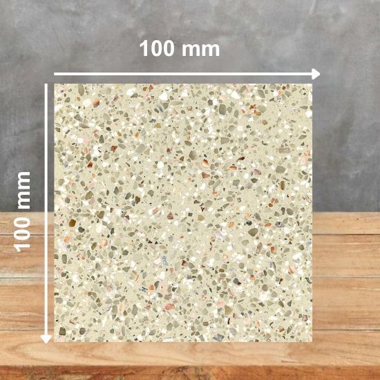 100 mm square sample of Quartzforms Terrazzo Goldoni quartz in light cream base with dense multicoloured grey beige pink and copper specks, displayed on wooden surface